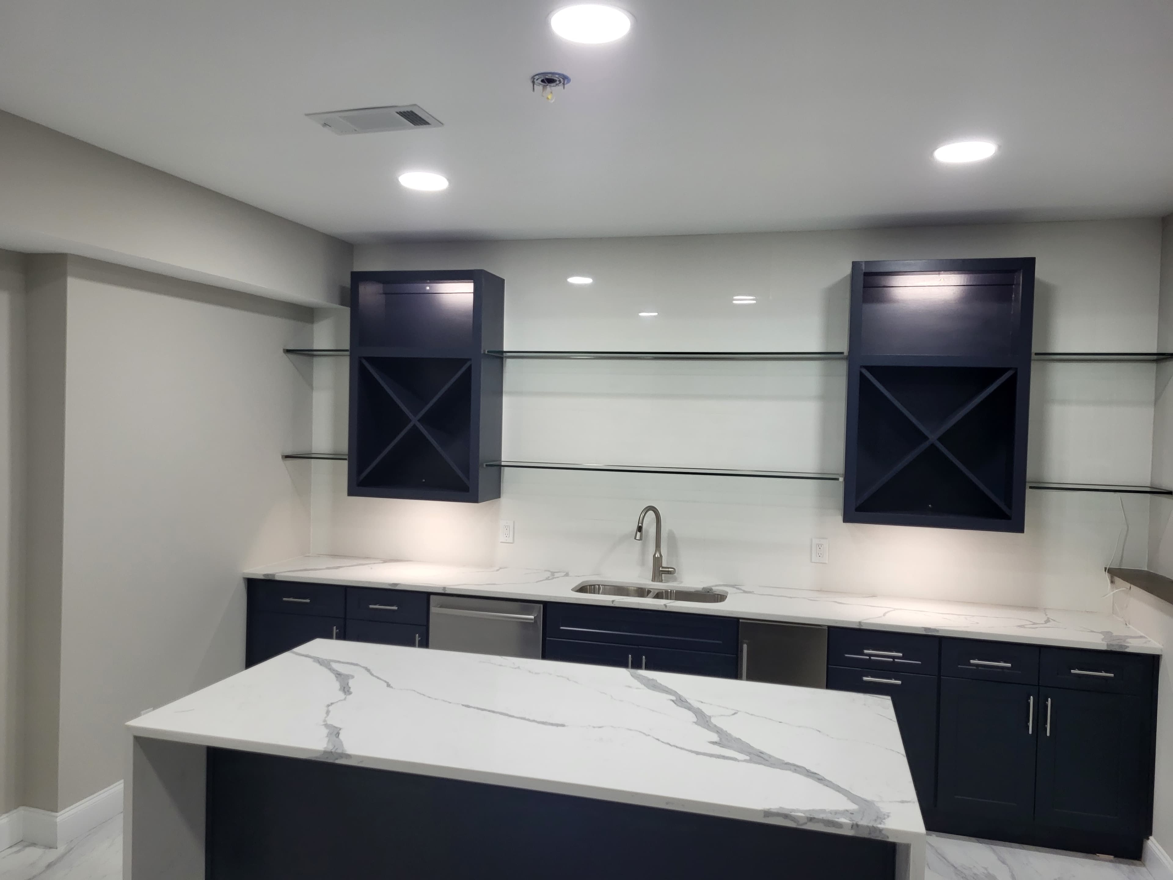 Finished navy wet-bar cabinetry with calacatta marble counters and X-pattern wine cabinets
