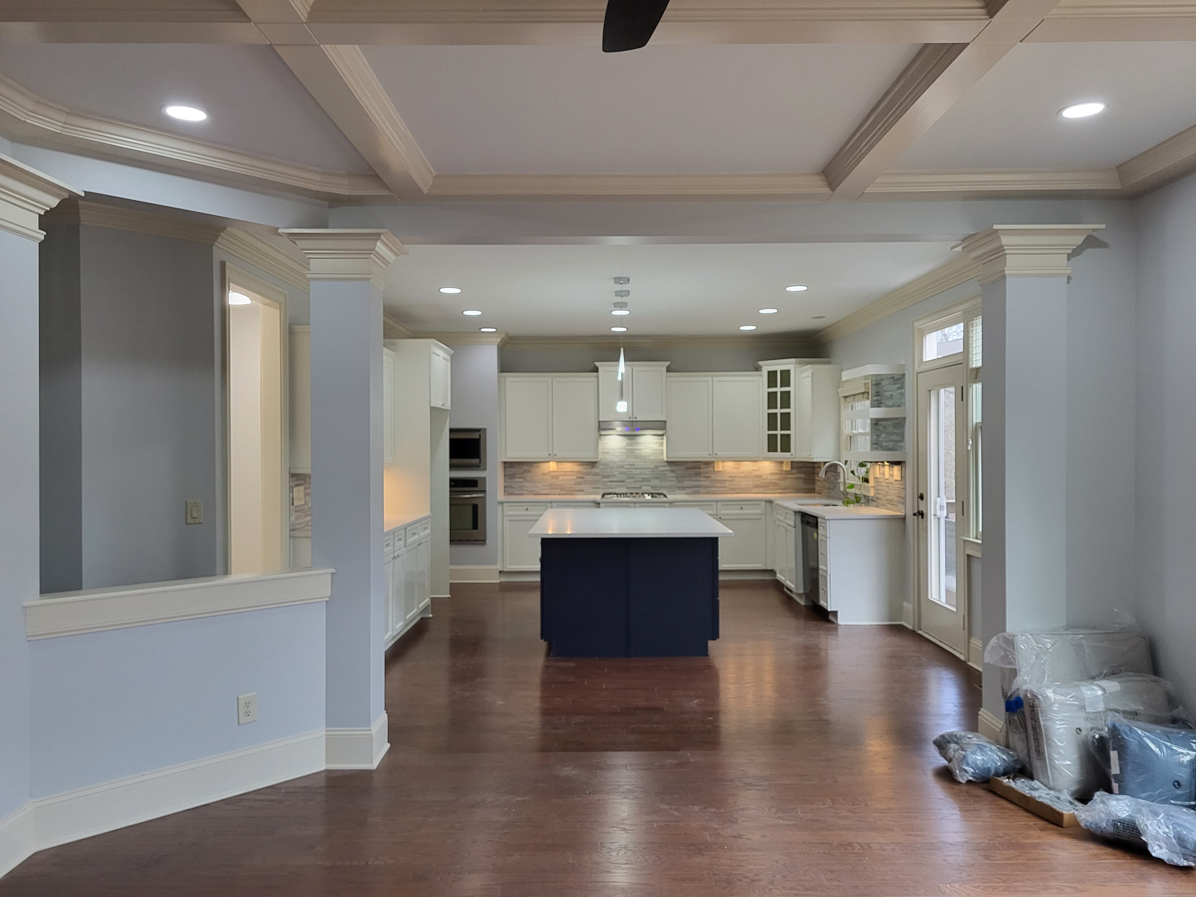 Open kitchen with painted coffered ceiling, navy island, and white cabinetry — after Bridgepointe
