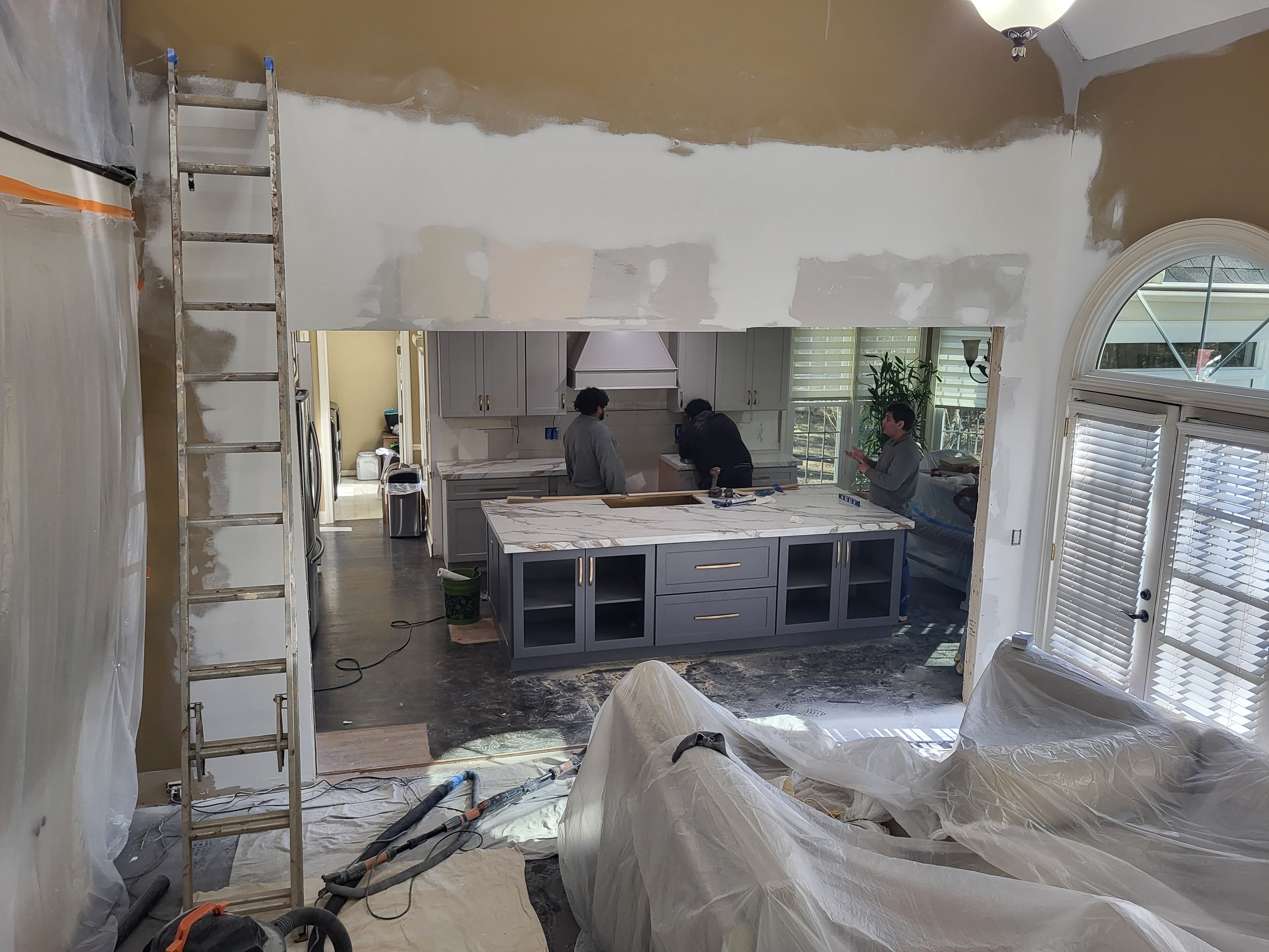 Mid-project cabinet repaint with mudded ceiling, ladders, drop cloths